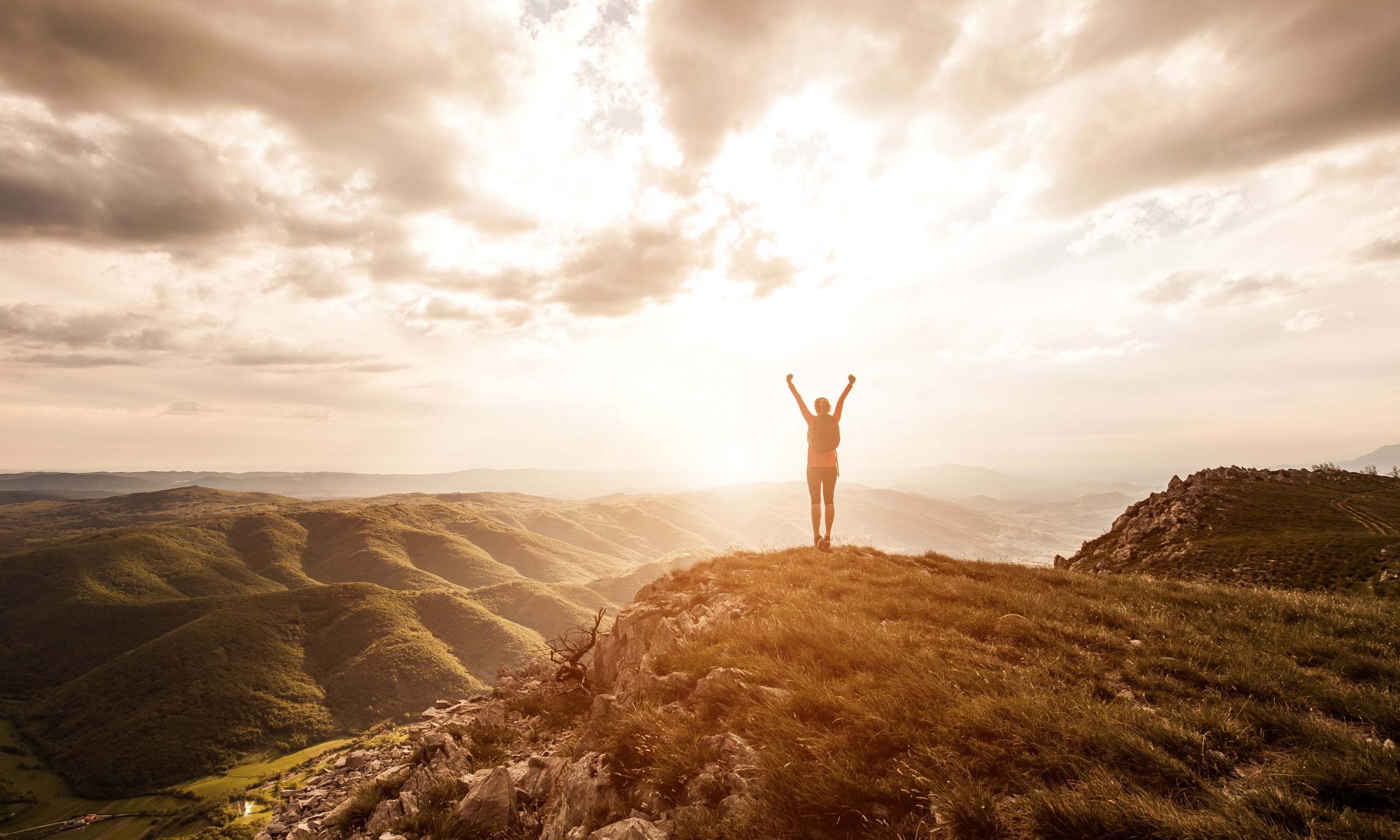 A hiker taking in an open mountain landscape at sunrise